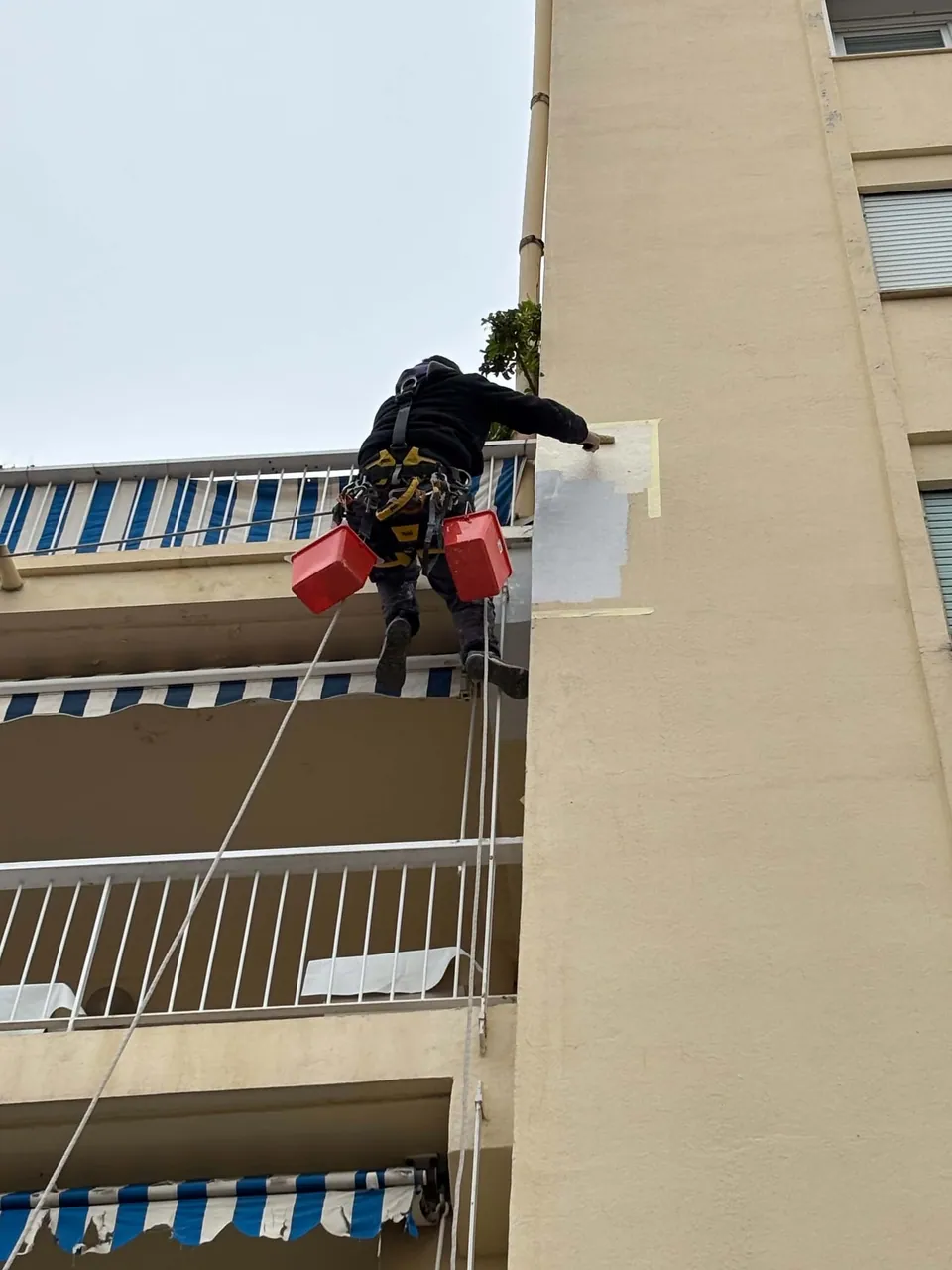 Application d'un revêtement de façade lors d'une intervention sur corde