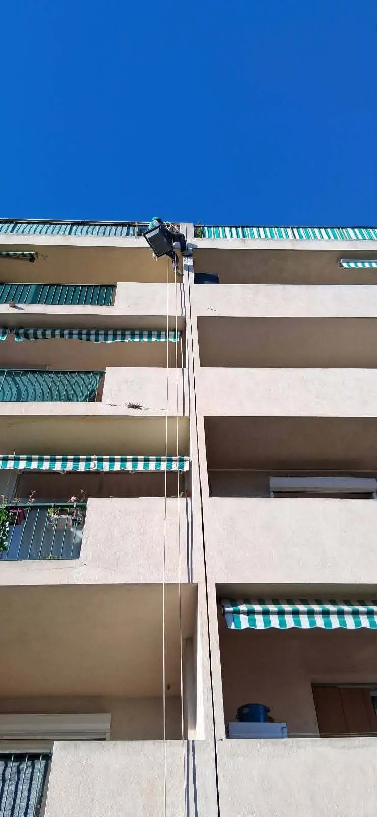 Technicien cordiste intervenant depuis le haut d'une façade